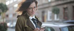 Jeune femme lisant un message sur son portable dans la rue
