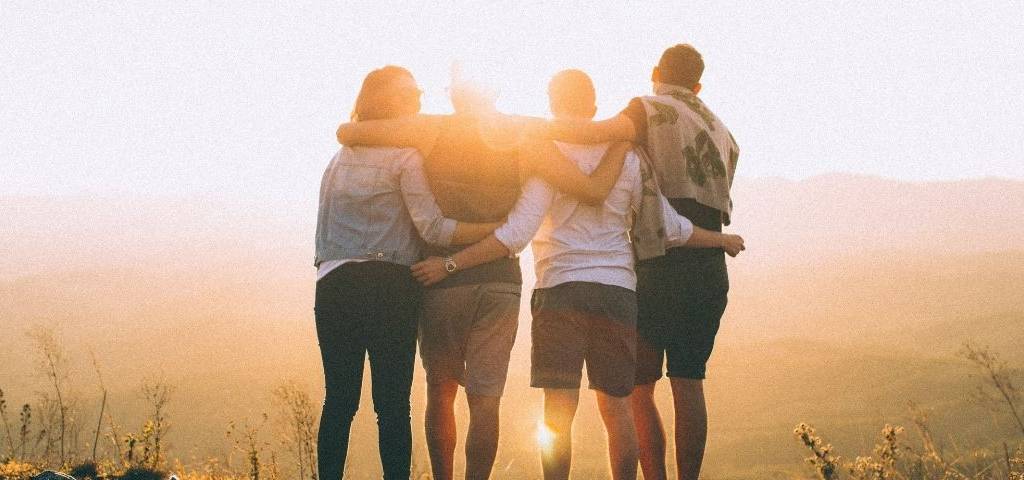 4 personnes de dos regardant le couché de soleil