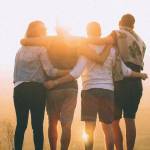 4 personnes de dos regardant le couché de soleil