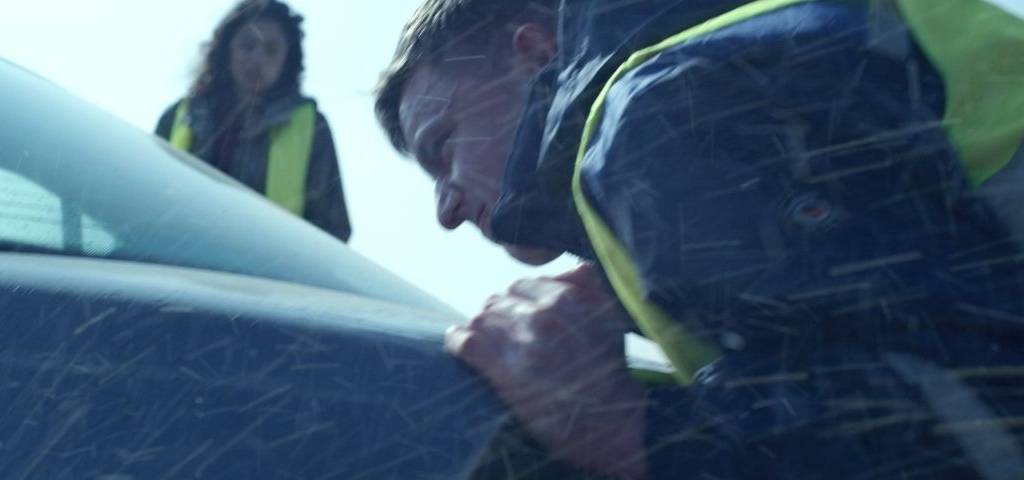 Homme poussant une voiture sous la pluie