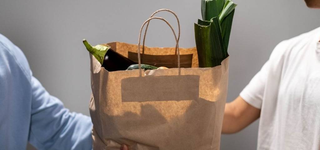 Publicis Conseil invite tous les acteurs de la chaîne de solidarité sont invités à rejoindre l’initiative Solidarité Associations pour faire face à la crise. Personne donnant un sac de nourriture à une autre personne