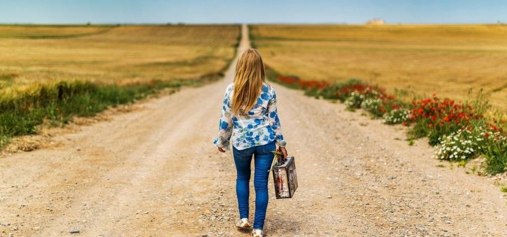 jeune fille marchant de dos sur un chemin à la campagne