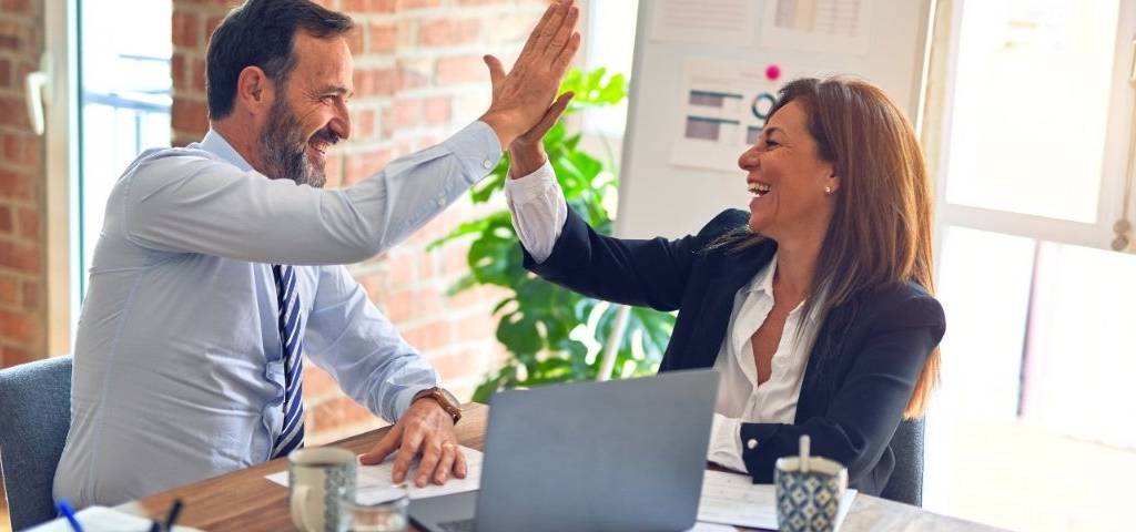 Une femme et un homme avec l'ai satisfait. Ils se tapent dans la main. Ils sont au bureau.
