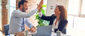Une femme et un homme avec l'ai satisfait. Ils se tapent dans la main. Ils sont au bureau.