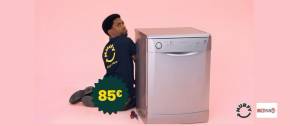 Un homme à coté d'une machine à laver sur un fond rose