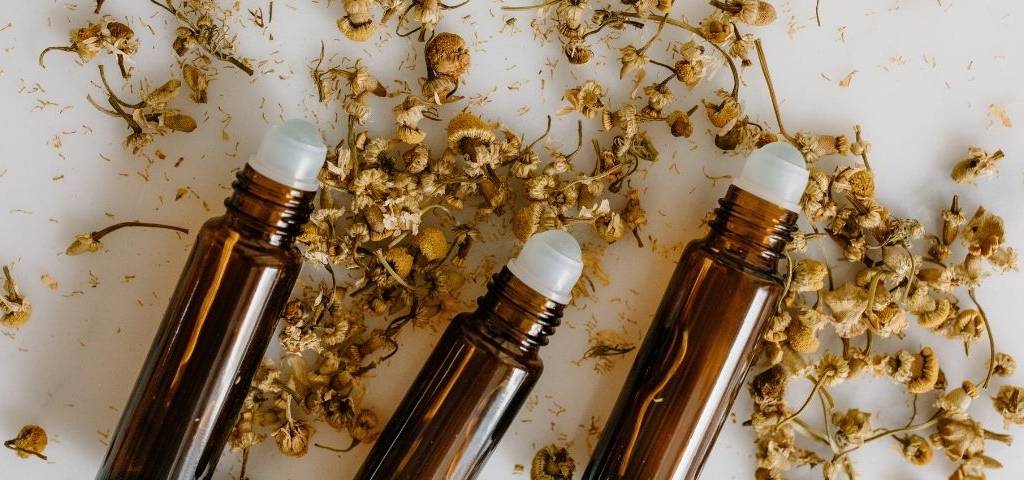 Plusieurs échantillons de parfum sur un lit de fleurs séchées