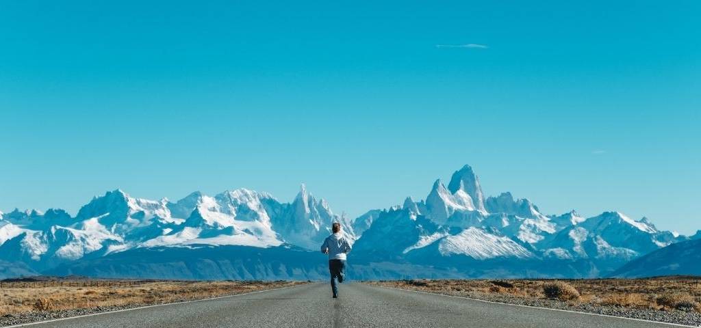 Un homme qui court sur une route sur le fond de montagnes eneigées