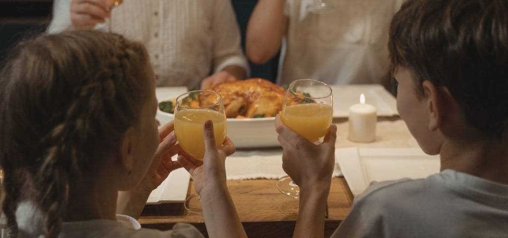 Deux enfants trinquant avec un verre de jus d'orange au restaurant