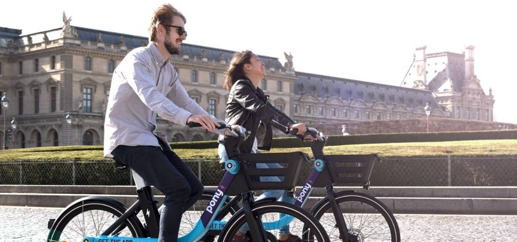 2 personnes souriantes sur des vélos électriques Pony