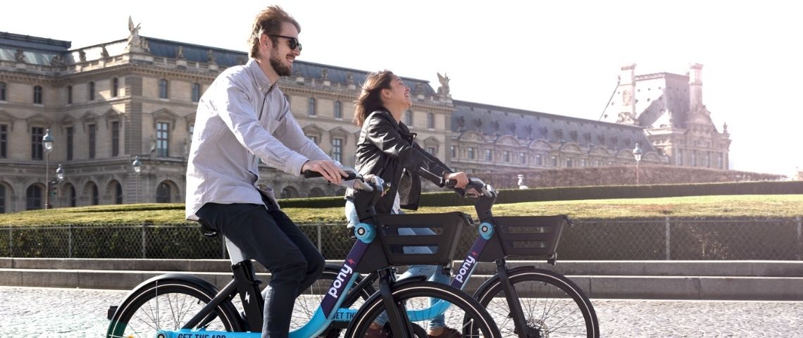Depuis début mars 2021, les Parisiens peuvent emprunter l'un des 500 vélos à assistance électrique partagés de pony le long des lignes 1 et 13 du métro. 2 personnes souriantes sur des vélos électriques Pony