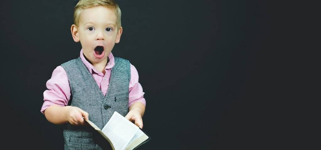 Un enfant déguisé en adulte, importe un costume et tient un livre dans sa main