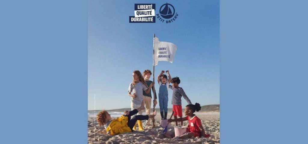 Campagne Petit Bateau - Enfants sur une plage autour d'un drapeau