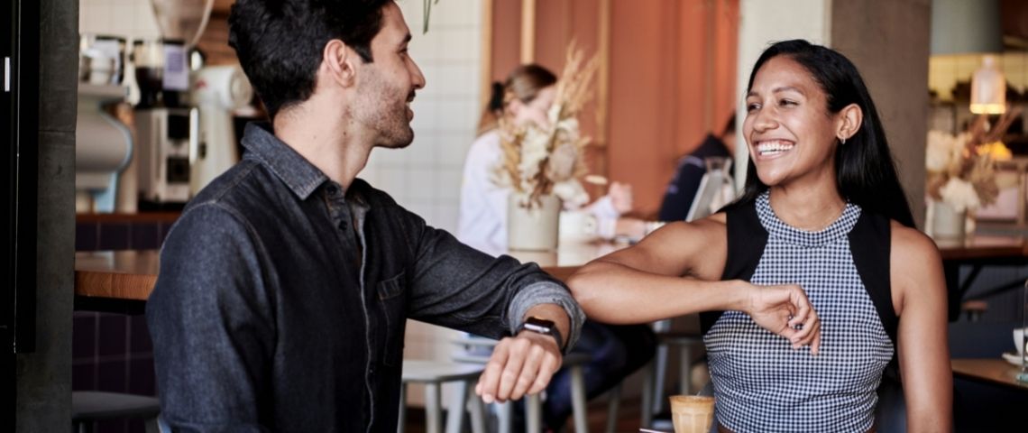 bumble-application-de-rencontre-amour-post-confinement-manifesto une femme et un homme dans un café qui se disent bonjour avec le coude (Covid 19 - gestes barrières )