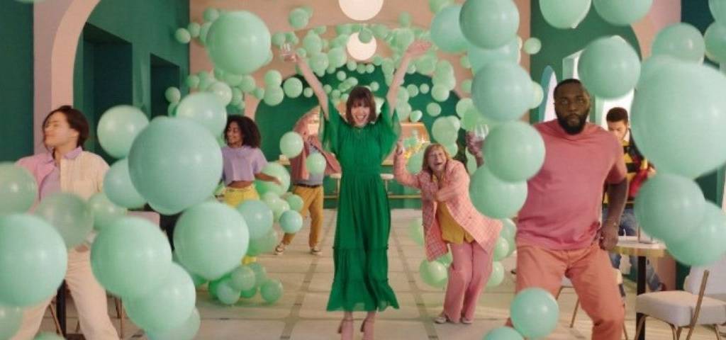 Une fête, une femme au milieu, ils semblent tous heureux, il y a des ballons partout