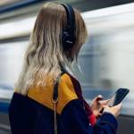 Une femme qui écoute du son au travers d'un casque de musique. Elle se trouve dans une station de métro