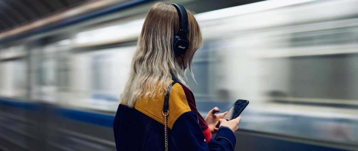 Nielsen-Audion-campagne-audio-annonceurs-agence-publicité-sonore-ciblage-UX Une femme qui écoute du son au travers d'un casque de musique. Elle se trouve dans une station de métro