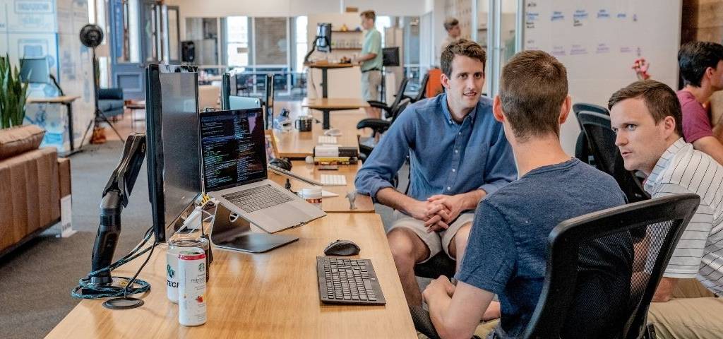 3 hommes qui discutent dans un bureau open space
