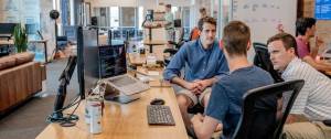 3 hommes qui discutent dans un bureau open space