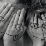 Deux enfants qui se cachent le visage avec leurs mains. Ils ont dessiné des smileys