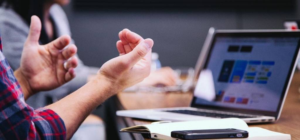 Des mains au premier plan. Un ordinateur au second