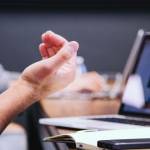 Des mains au premier plan. Un ordinateur au second