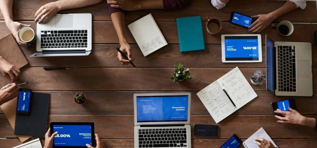 MediaConnect propose un service qui vise à fluidifier et simplifier les relations entre les journalistes et les communicants des institutions, entreprises et ONG Personnes autous d'une tabl aec des écrans d'oridinateur, de tablettes et de smartphones