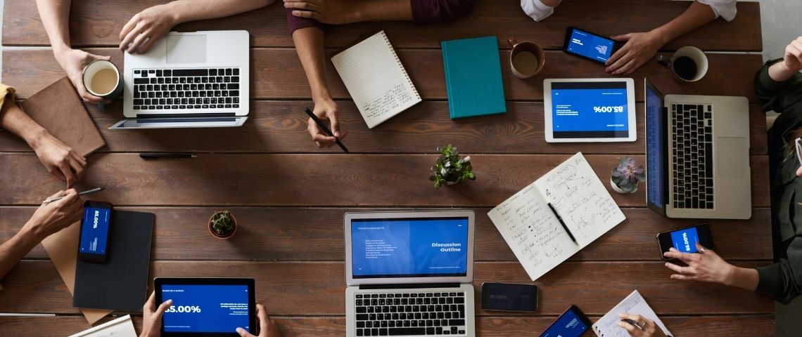 MediaConnect propose un service qui vise à fluidifier et simplifier les relations entre les journalistes et les communicants des institutions, entreprises et ONG Personnes autous d'une tabl aec des écrans d'oridinateur, de tablettes et de smartphones