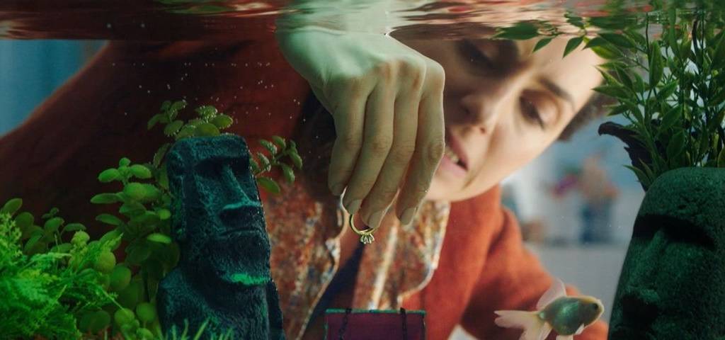 Groupama, accompagné par l'agence Marcel, communique sur son offre de télésurveillance à domicile Femme mettant une bague dans un petit coffre fort dans un aquarium
