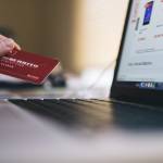 Personne tenant une carte bancaire devant un ordinateur