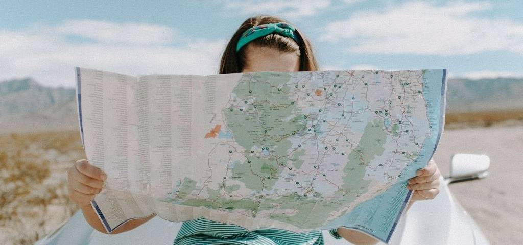 Jeune femme assisie sur le vapot d'une voiture regardant une carte
