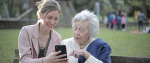 Jeune femme et personne âgées sur un banc avec un smartphone