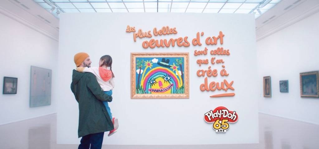 Papa tenant un enfant dans ses bras dans un musée, devant un tableau