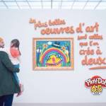 Papa tenant un enfant dans ses bras dans un musée, devant un tableau