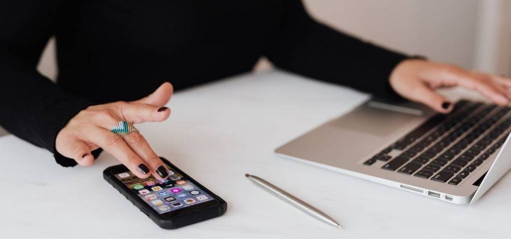 Main d'une femme avec un ordinateur et un téléphone portable