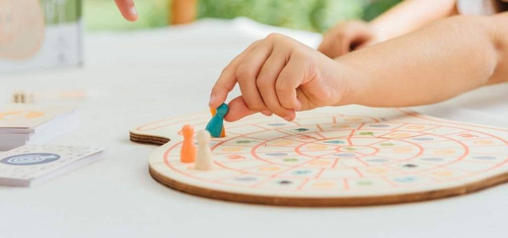 Enfant déplaçant un pion sur un plateau de jeu en bois