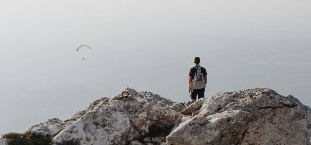 Un homme en haut d'une montagne. Il regarde au loin