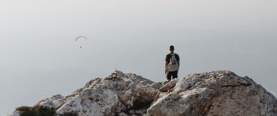 Un homme en haut d'une montagne. Il regarde au loin
