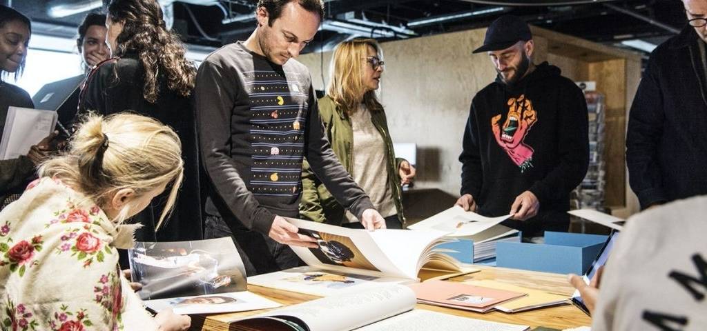 Des femmes et des homme autour d'une table qui regarde des maquettes/book