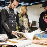 Des femmes et des homme autour d'une table qui regarde des maquettes/book