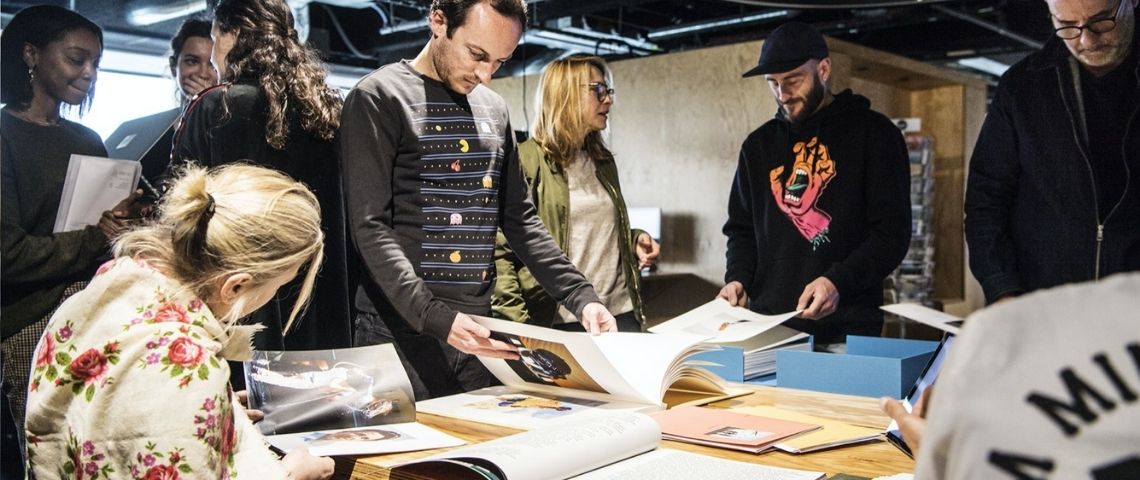 Havas-group-rse-programme-Havas-Impact-environnement-engagement-ecoresponsabilite Des femmes et des homme autour d'une table qui regarde des maquettes/book