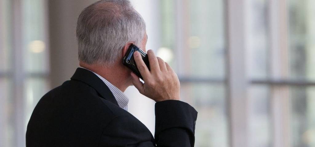 Un homme au téléphone. Il est en costume. Bureau