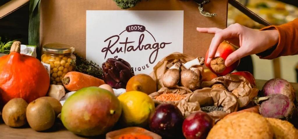 Des fuits et légumes. Une main saisit une noix. Un sac de la marque Rutabago en fond.
