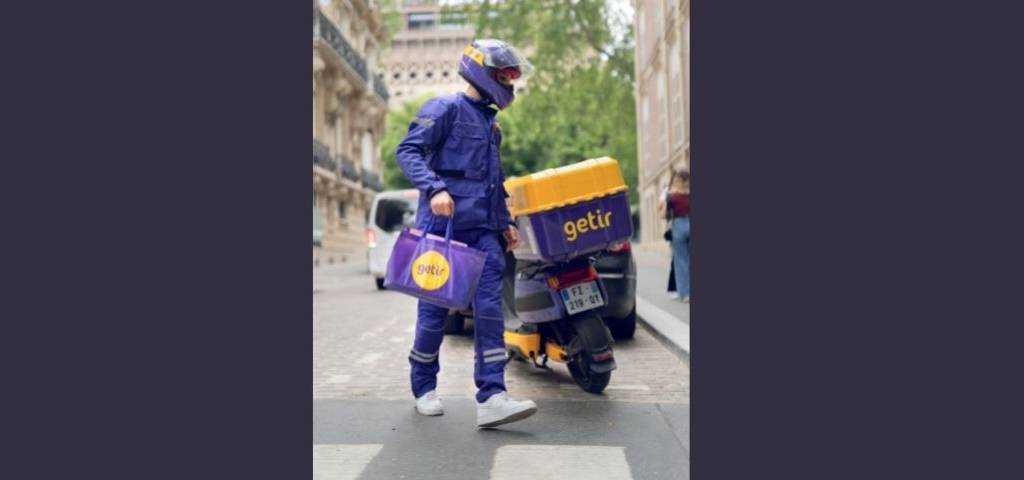 Un livreur à domicile à coté de son scooter