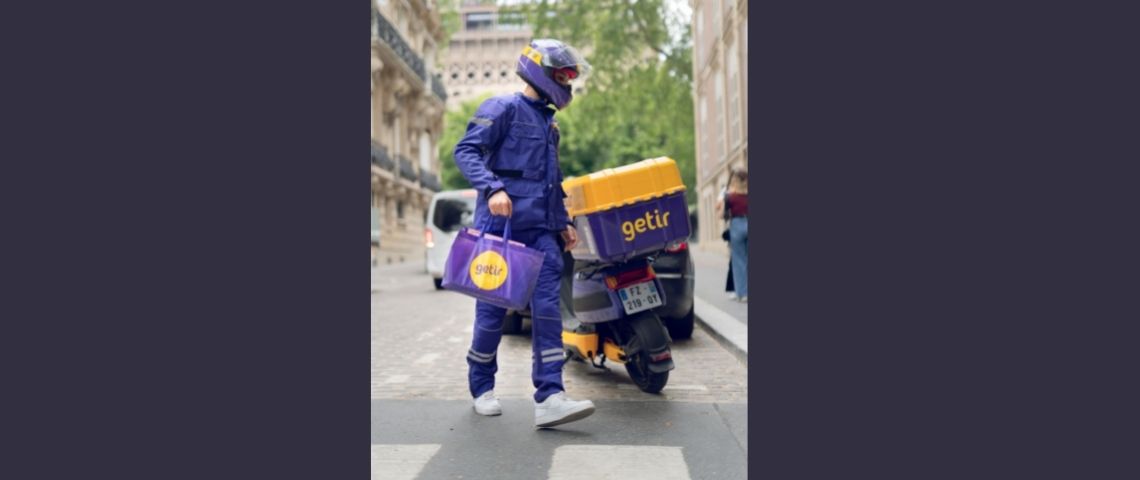 getir-livraison-rapide-produits-depicerie-paris-europe-service Un livreur à domicile à coté de son scooter