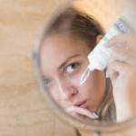 Une femme qui se regarde dans un miroir et met de la crème
