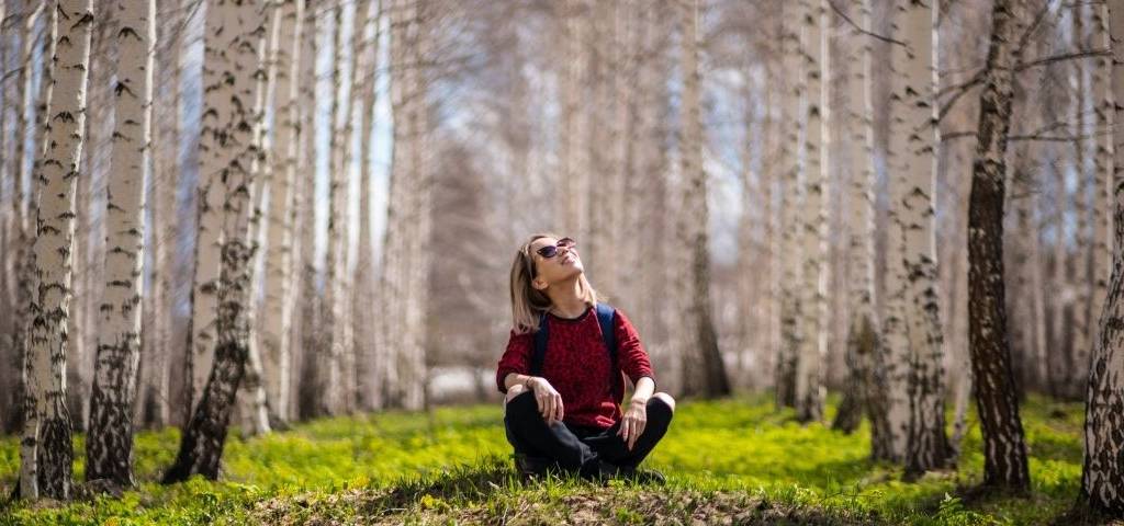 jeune femme assise dans l'herbe regardant le ciel