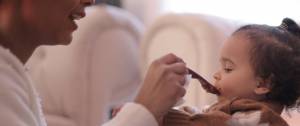 Mmaan donnant à manger à son enfant à la petite cuillère