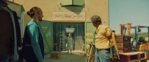 Femme sortant de sa boutique avec 2 hommes devant