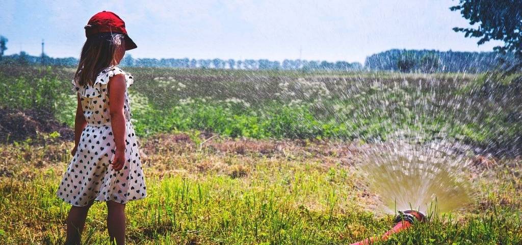 jeune fille dans un jardin avec un arrosage