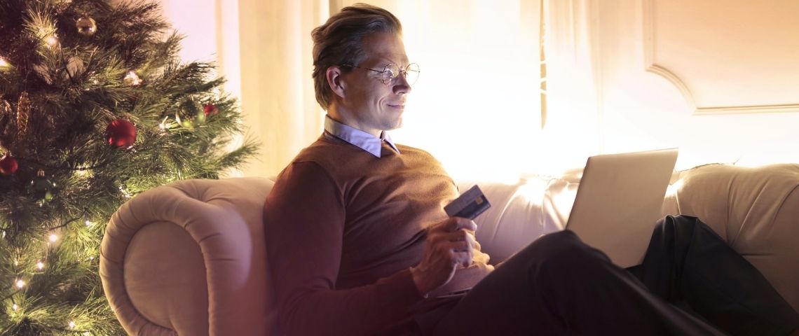 Rakuten lance son premier Live Shopping, en mode inclusif en en partenariat avec la plateforme Quidol Homme sur un canapé, avec une carte bancaire à la main, devant un ordinateur